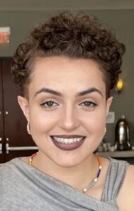 A photo of a smiling young woman with curly dark hair.