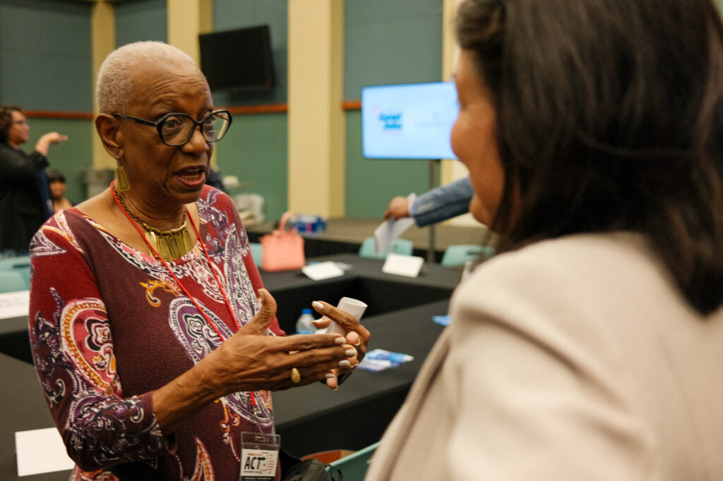 Two women are pictured speaking to each other. 