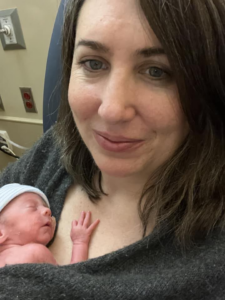 A white woman with brown hair holding a newborn baby.
