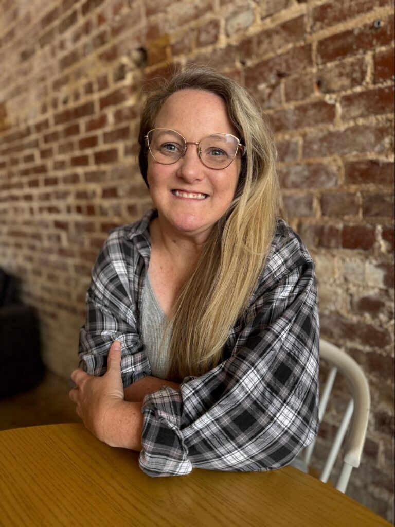 An adult woman sits at a table. 