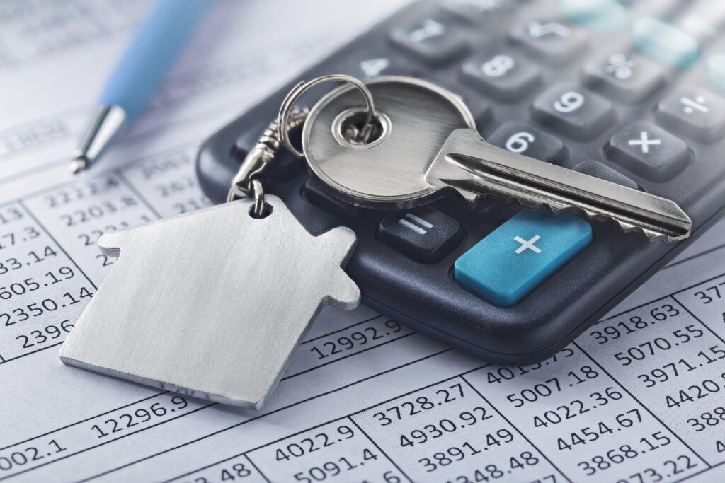 Photo of piece of paper with numbers on it. On top of the paper are a pen and a calculator. A key chain is atop the calculator.
